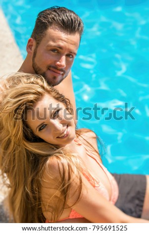 Woman and man enjoy the sun at the edge of the pool