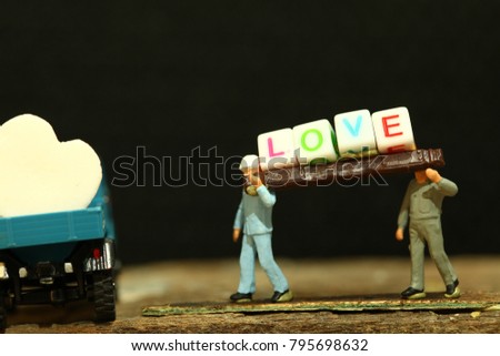 Construction worker figure model carrying pieces of text cube spelling word love meaning and represent valentine day and love concept idea.