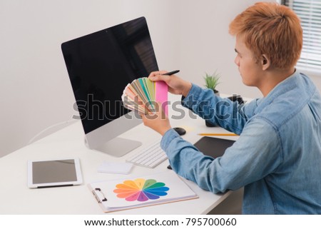 Serious male graphic designer looking at pictures in digital camera at office