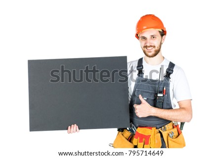 Full length portrait of a male construction worker with a white blank banner over a white wall background. repair and construction. Isolated over white background