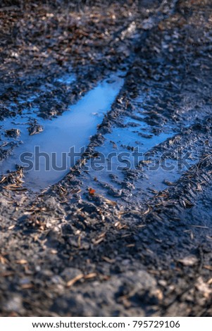 Dirty rural road with mud and water in autumn time
