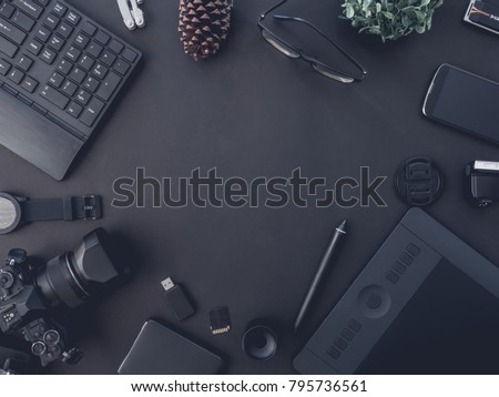 top view of graphic design and photographer concept with digital camera, memory card, smartphone, graphic tablet, and keyboard on black background with copy space