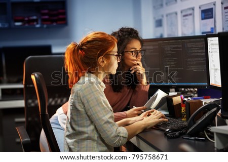 Two female programmers working on new project.They working late at night at the office. Royalty-Free Stock Photo #795758671
