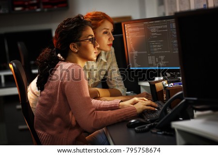 Two female programmers working on new project.They working late at night at the office. Royalty-Free Stock Photo #795758674