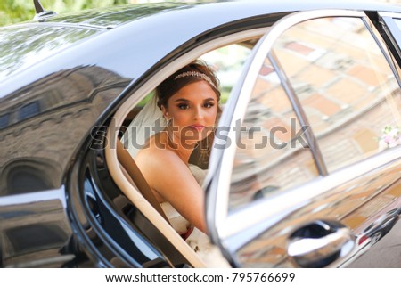 Wedding day. Bride sitting in wedding car, looking aside and smiling 