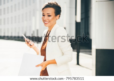 Smiling happy businesswoman standing with the phone.