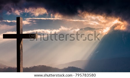 Jesus Christ cross. Easter, resurrection concept. Christian wooden cross on a background with dramatic lighting, colorful mountain sunset, dark clouds and sky, sunbeams  Royalty-Free Stock Photo #795783580