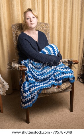 Woman in late twenties daydreaming  at home with a blue blanket 