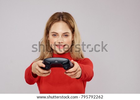  smiling woman holding a joystick on a gray background                             