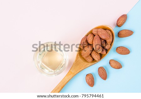 Peeled almonds seeds with almond oil on color paper background with empty space for your text or message. Royalty-Free Stock Photo #795794461