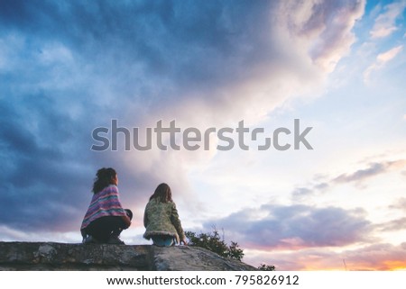 Young family sitting on roof and looking at the sunset