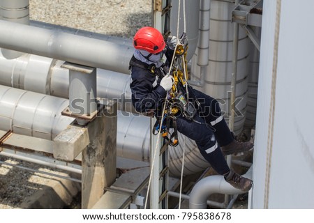 Top view male worker rope access  inspection of plumbness storage tank industry below pipeline oil