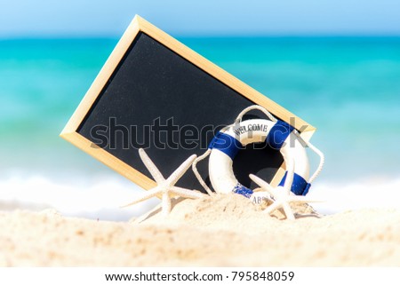 Closeup of a chalkboard for written, lifebuoy and starfish on the sand of a beach.  Summer Concept