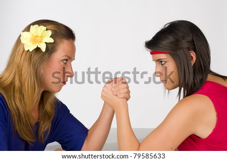 Blond and Hispanic girl competing by arm wrestling