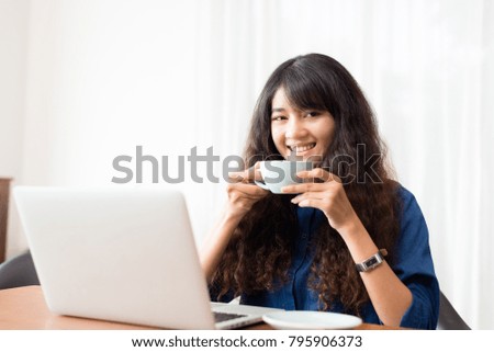 Young woman or student using laptop sitting at coffee shop. Happy girl working online or studying and using notebook. Freelance business concept.