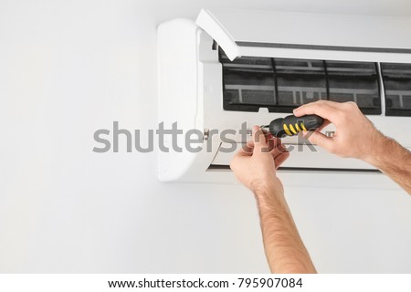 Male technician fixing air conditioner indoors Royalty-Free Stock Photo #795907084