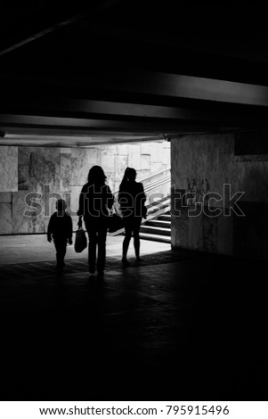 Family: son, daughter and mother come out of the underpass, black and white photo