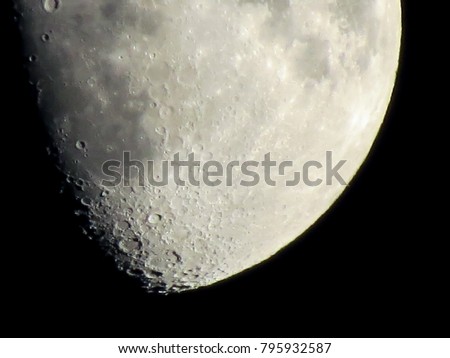 Bottom of the moon in part shadow in the black night sky showing details of the lunar surface.