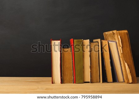 Educational background. Books against empty classroom blackboard for copy space. Back to school concept