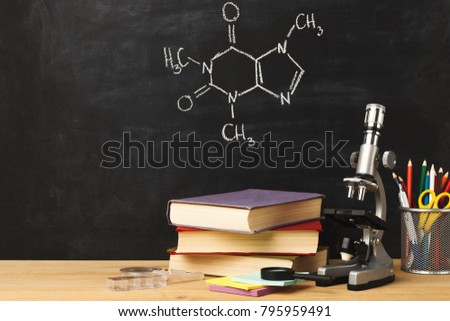 Studying chemistry educational background. Microscope, books and colorful liquids at classroom blackboard with chalk drawing of molecular structure. Back to school, experiment and research concept