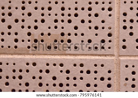 Dingy white tile with dirt and tapemarks, and round perforations of varying sizes. 