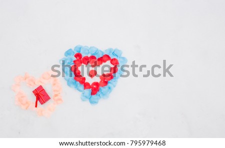 Flat lay photo of hand gesture half heart ,  made of violet purple pink rose flowers petals on white snow, and  gift jewelry box .Heart-symbol of love, Valentines Day, 14 February .Copy space photo.