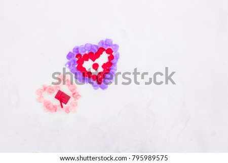 Flat lay photo of  , heart  made of red and purple , red and pink  rose flowers petals and a gift jewelry box  on white snow . Heart-symbol of love, Valentines Day , 14 February .Copy space photo.
