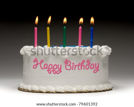 White birthday cake profile on gradient background with five colorful lit candles and "Happy Birthday" written on the side with frosting