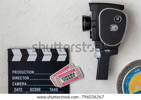 Clapperboard, an old movie camera, a tin box with a film and two tickets to the cinema.View from above.
