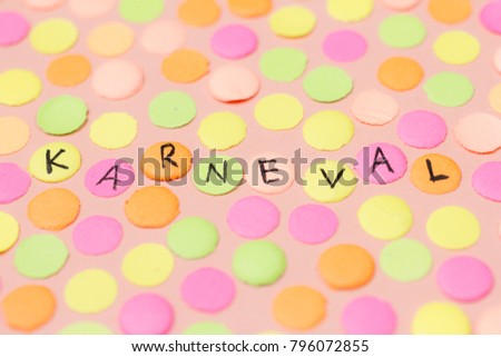 Hand written the word in German language Karneval in each colorful confetti. Warm colors: pink, yellow and orange. Carnival party background concept, space for text.