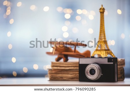 Vintage camera with Eiffel tower and airplane with books on background. Adventure dreams concept