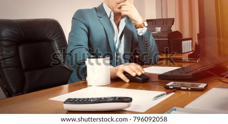 A businessman working on computer with a cup of tea and telephone