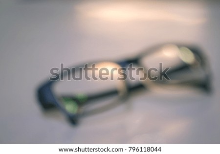 blur background of glasses frame on white desk with orange sun ray