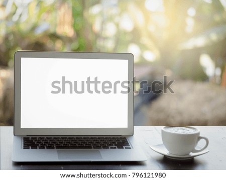Laptop on wooden table with cup coffee blurred background.