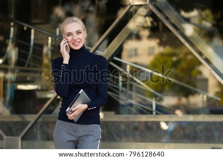 Beautiful business woman uses a tablet and speaks by phone . Student using tablet and speaks by phone in the outdoor .  Royalty-Free Stock Photo #796128640