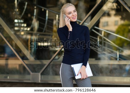 Beautiful business woman uses a tablet and speaks by phone . Student using tablet and speaks by phone in the outdoor .  Royalty-Free Stock Photo #796128646