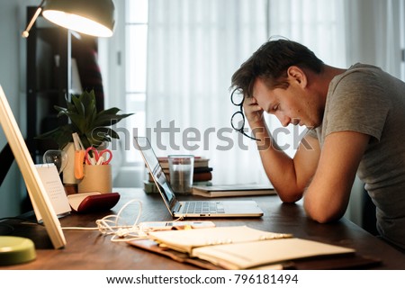 Man stressed while working on laptop Royalty-Free Stock Photo #796181494