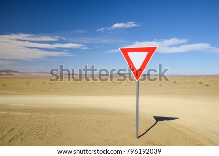 Wide angle view of a give way (yield) sign at a gravel road intersection in the Namibian Desert between Ai-Ais Fish River Canyon and Aussenkehr. Mountains in the background.
