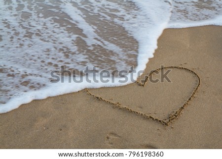 heart is written on the sand and the footprints are being washed away by the sea.