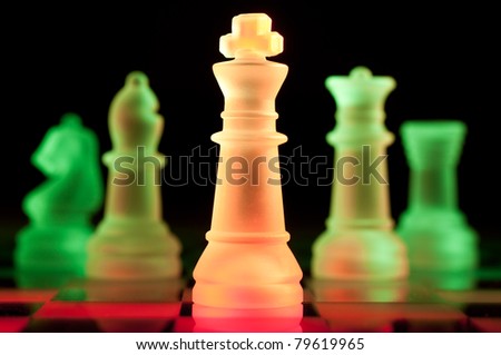 red and green glass chess pieces is standing on board in dark
