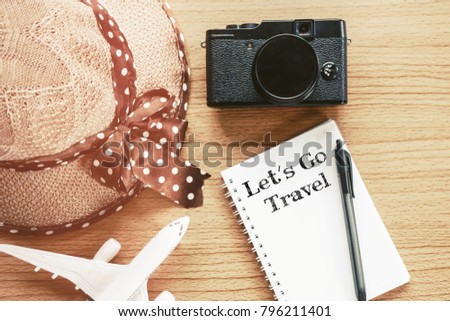 Travel concept - Let's Go Travel word written on notepad. Traveller object on wooden desktop
