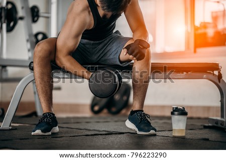Bodybuilder working out with dumbbell weights at the gym.man bodybuilder doing exercises with dumbbell. Fitness muscular body  Royalty-Free Stock Photo #796223290