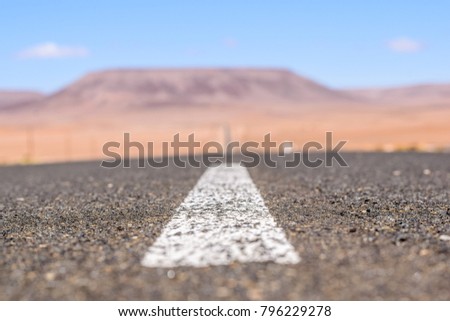 Close up view of the B4 road between Lüderitz and Keetmanshoop near Garub in Namibia, Africa. The road cuts through the famous Namib Desert. Mountains in the background. Selective focus. 