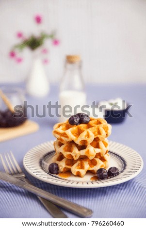 purple coloed breakfast- waffles with blueberries and honey syrup and milk