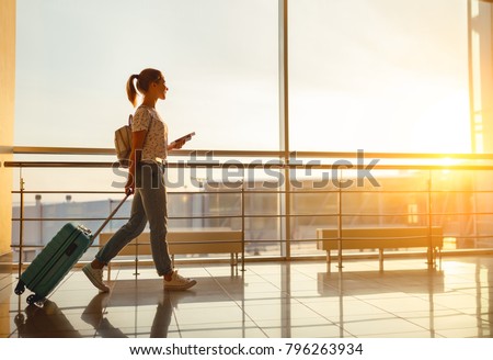 young woman goes  at airport  at window  with a suitcase waiting for  plane Royalty-Free Stock Photo #796263934