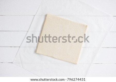 Puff pastry frozen sheet white parchment background.