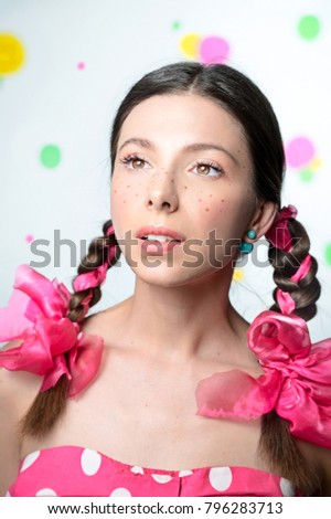 Portrait of teen girl with freckles and pigtails with pink bows 