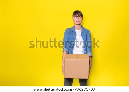 pretty woman standing on yellow background with moving cardboard box