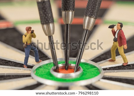 miniature people with dart in bull's eye, close up concept