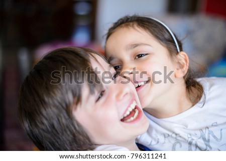 children brothers kiss on the cheek laughing and playing at home